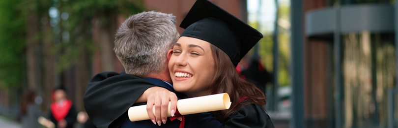 A woman hugs her dad with her new diploma