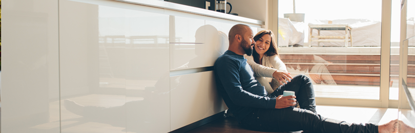 A couple sits on the floor of their newly renovated kitchen